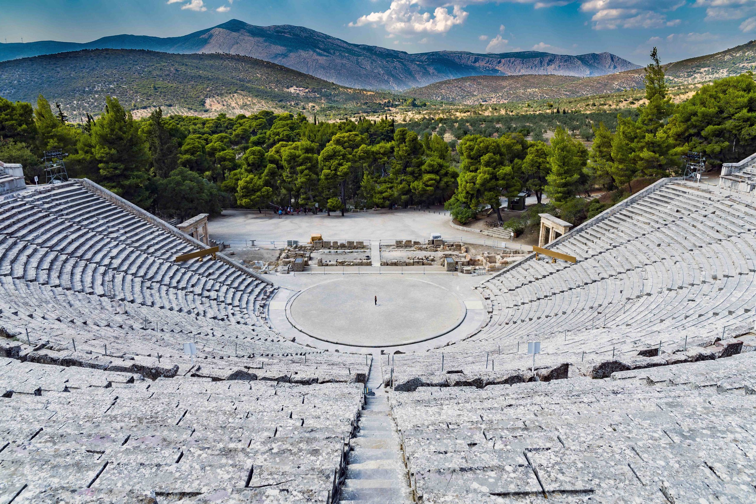high-shot-amphitheater-made-out-stone-with-green-trees-mountains-background